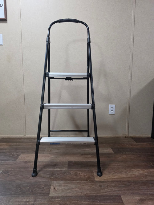 Straight-on view of the open Cosco three-step ladder with black frame and silver steps.