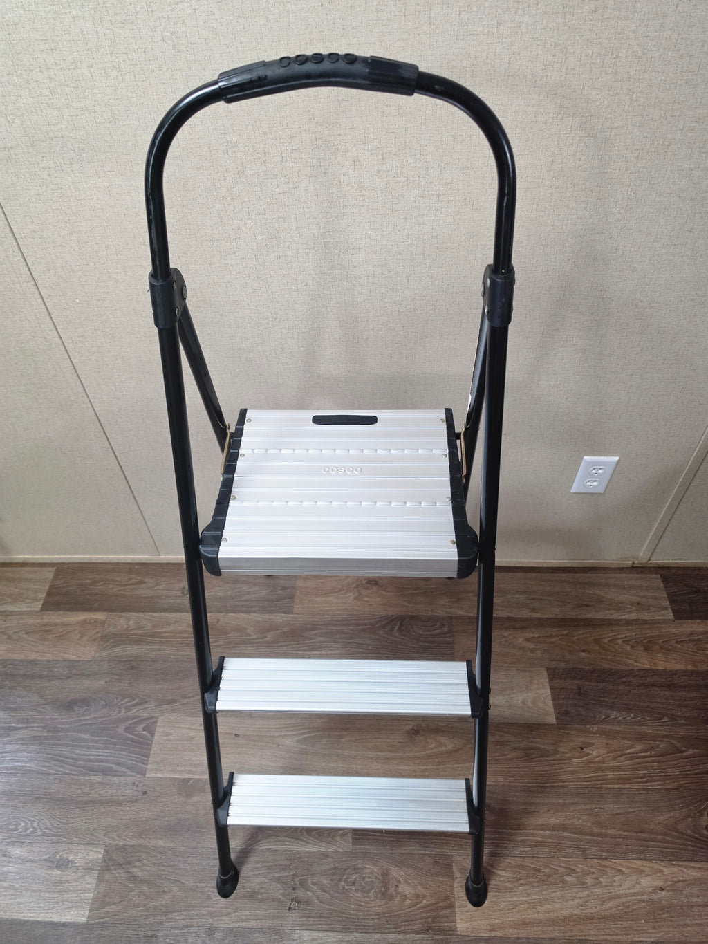 Front-right angled view of the open Cosco three-step ladder with nonslip steps.