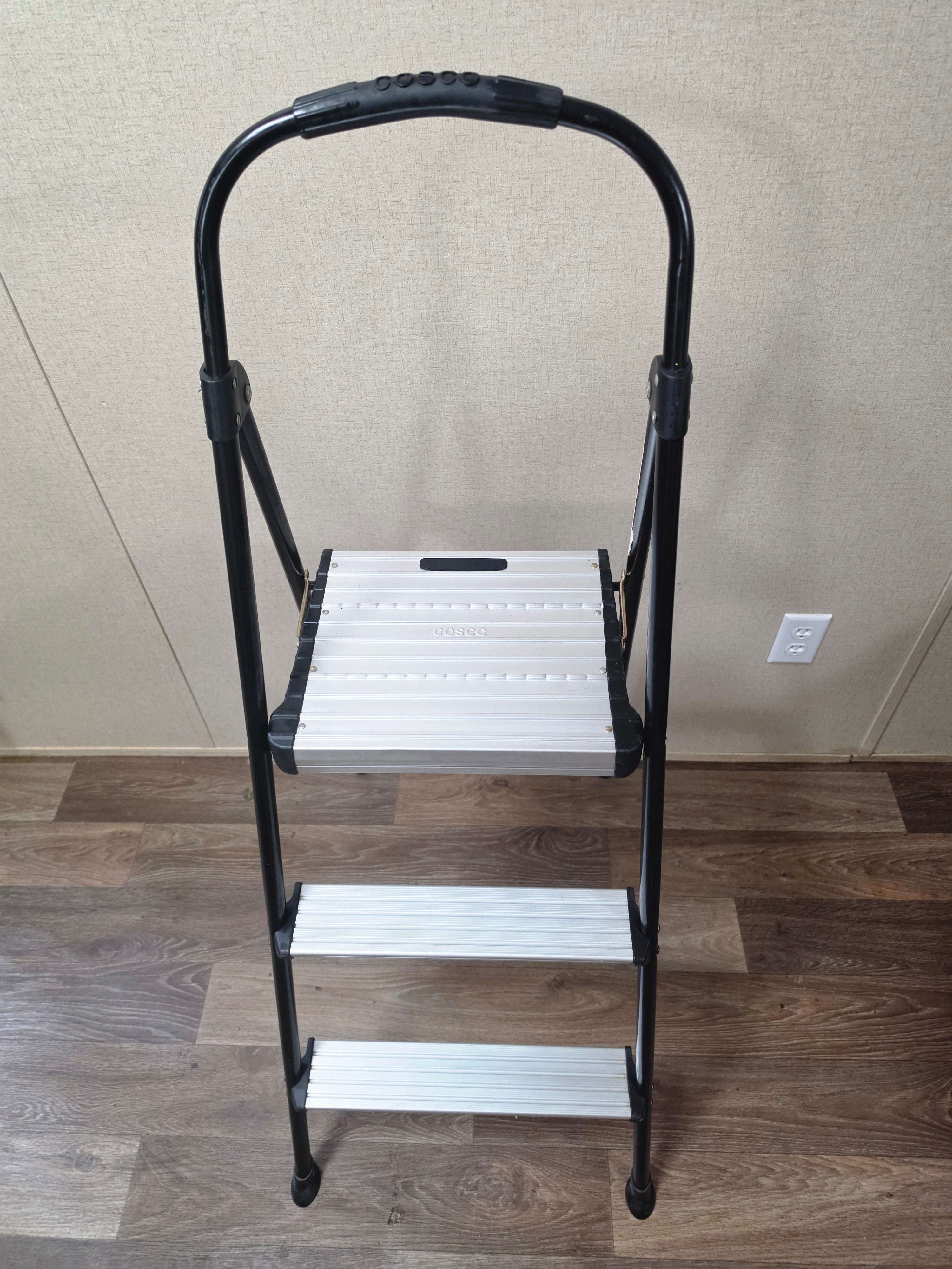 Front-right angled view of the open Cosco three-step ladder with nonslip steps.