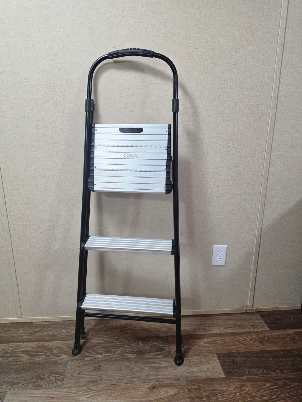 Cosco three-step ladder folded upright for compact storage.