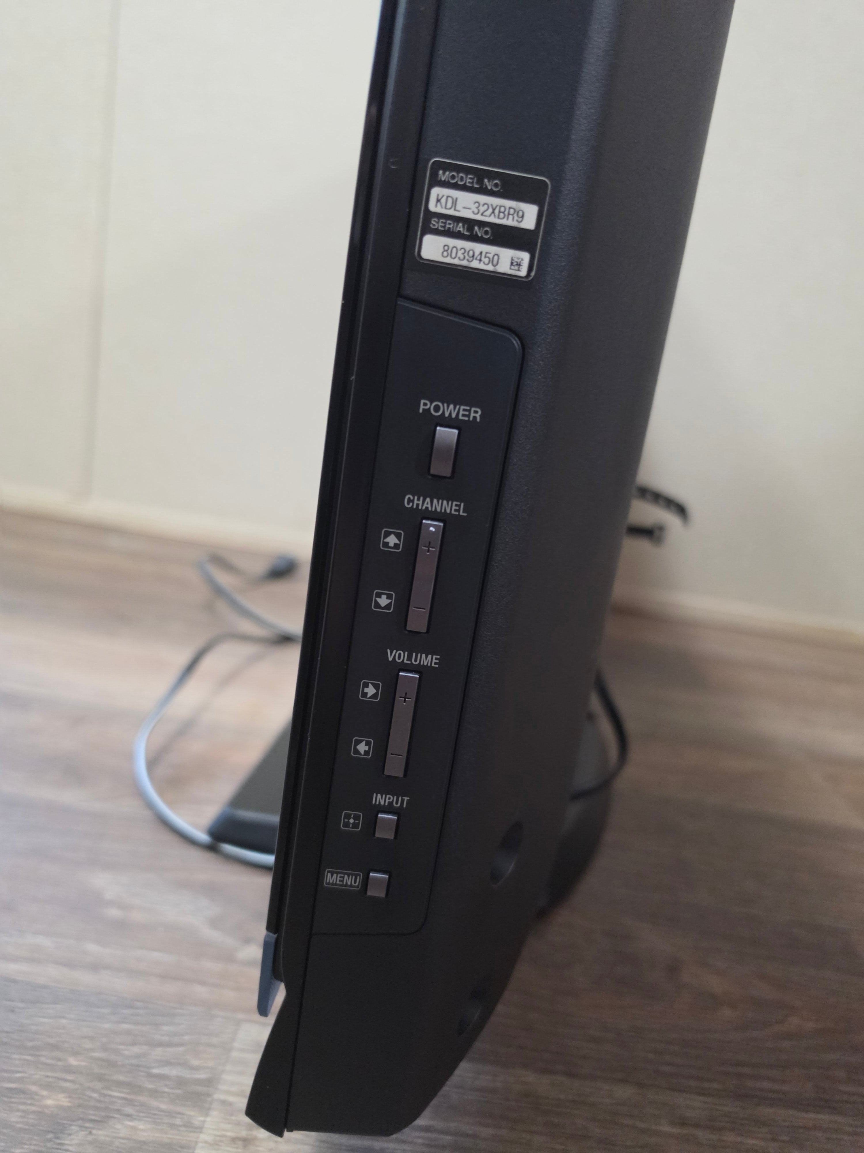 Close-up of the Sony Bravia TV side controls for power, channel, volume, and input.