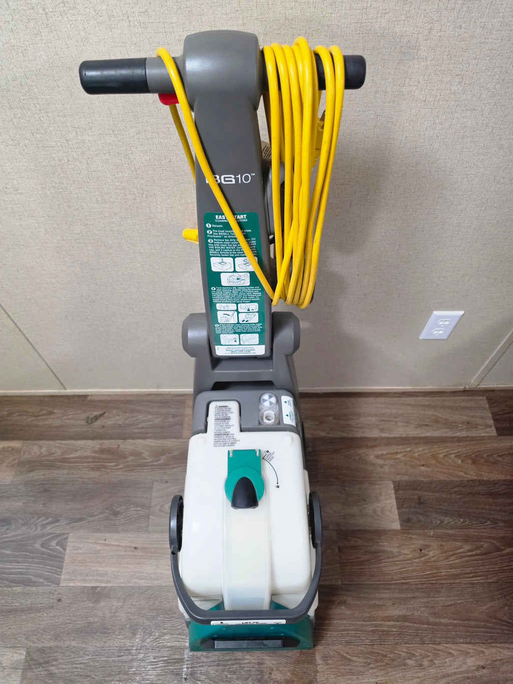 High front view of the BISSELL BigGreen cleaner showing the wrapped cord, handle labels, and tank controls.