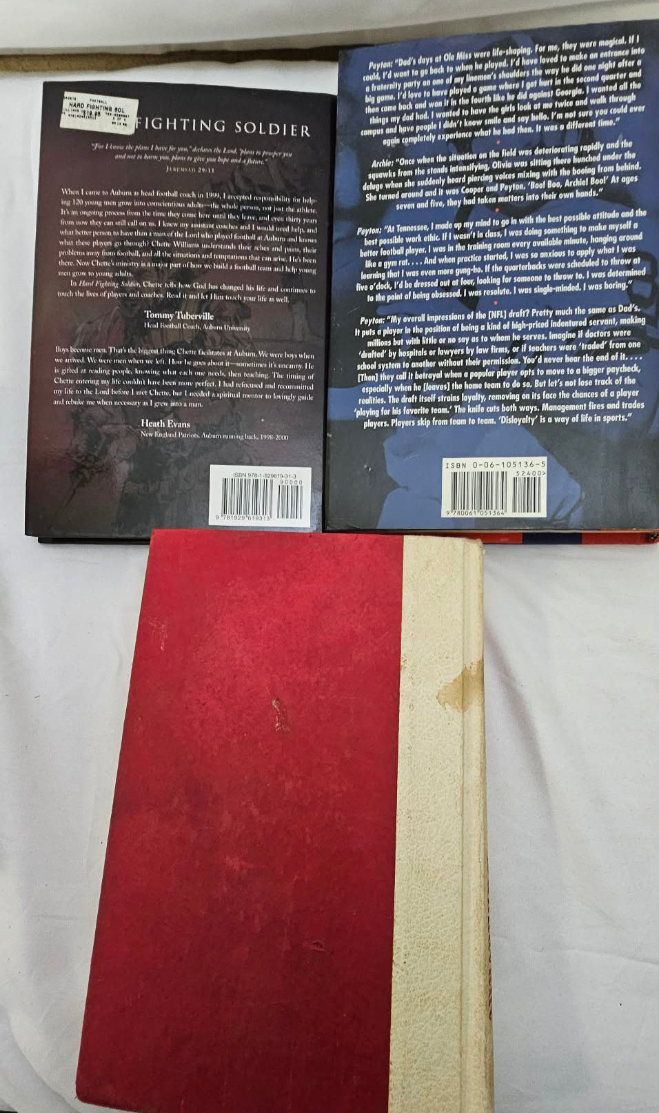 Back covers of two football books displayed above red and cream hardcover books.