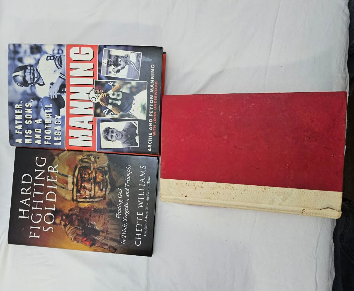 Manning and Hard Fighting Soldier football books beside a red hardcover book.