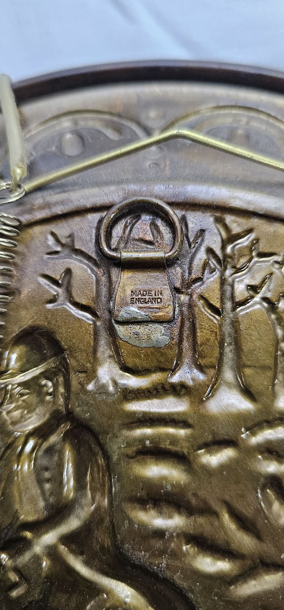 Close-up of the Made in England stamp, patina, and hanger hardware on the back of the second brass-tone wall plate.