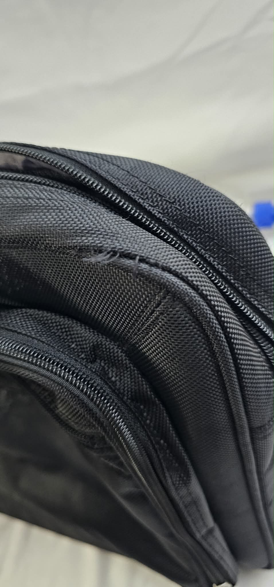 Close-up of the small frayed and worn area along the upper pocket seam near a zipper on the Dell briefcase.