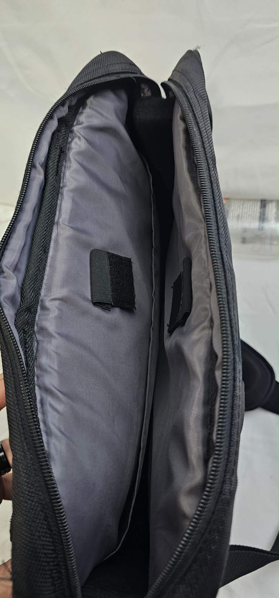 Open padded laptop compartment inside the black Dell briefcase with securing tabs and gray lining.
