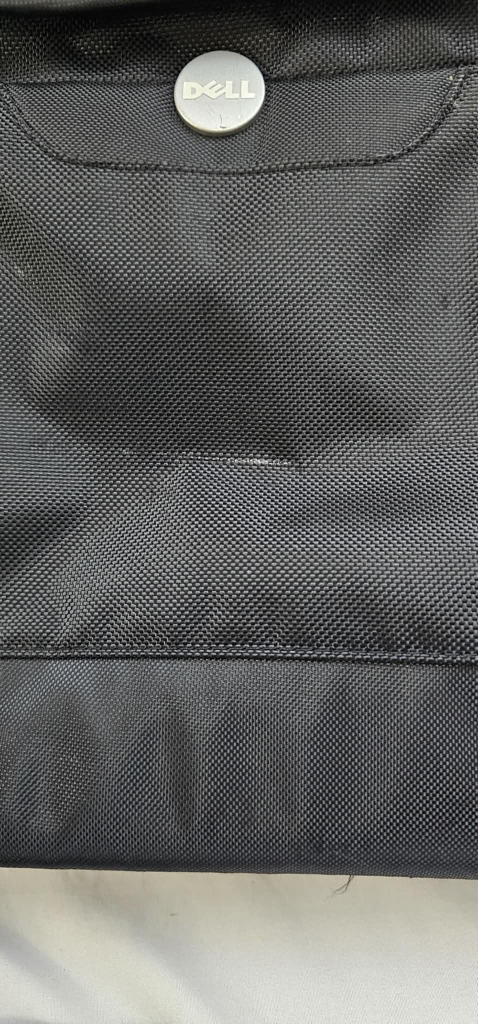 Close-up of the Dell logo and visible horizontal rubbing and scuffing on the black exterior fabric.